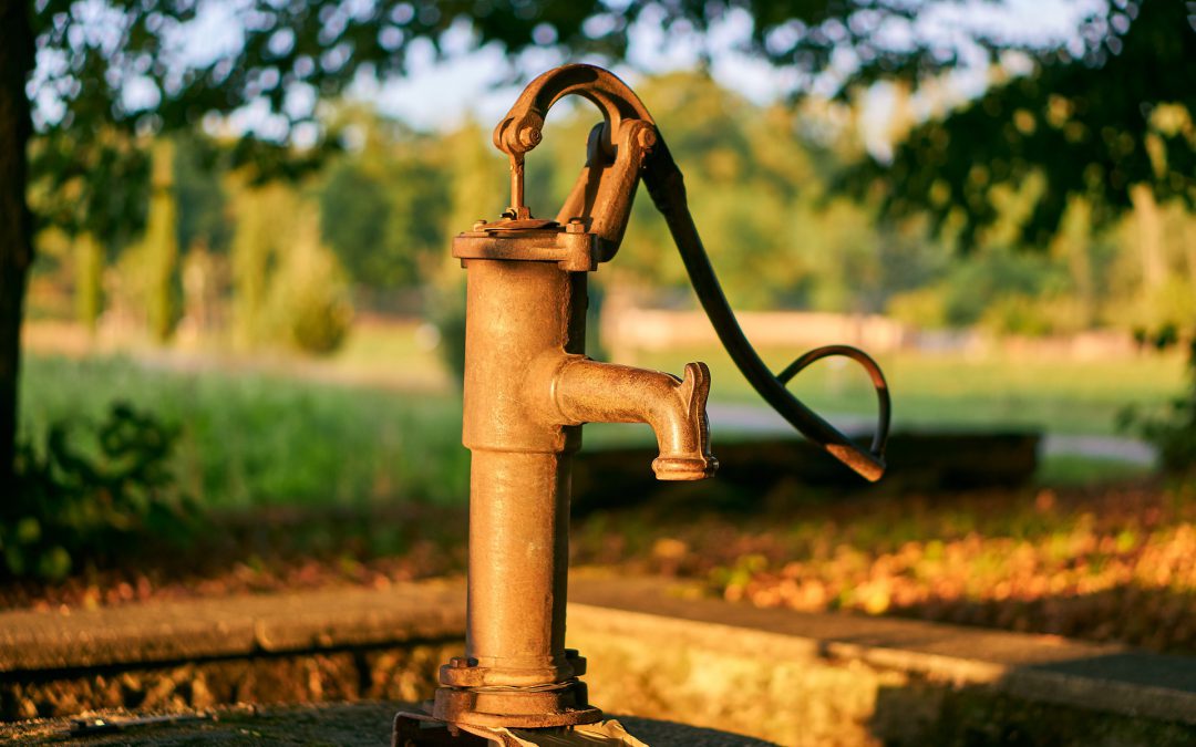 Alte Pumpe für einen Brunnen vor Feld