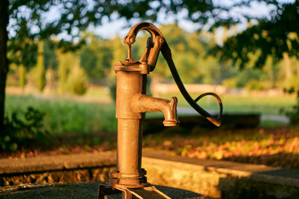 Alte Pumpe für einen Brunnen vor Feld